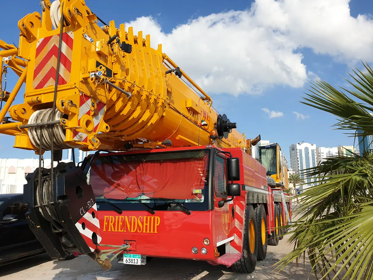 Close-up of a red FRIENDSHIP crane carrier cab and yellow boom head